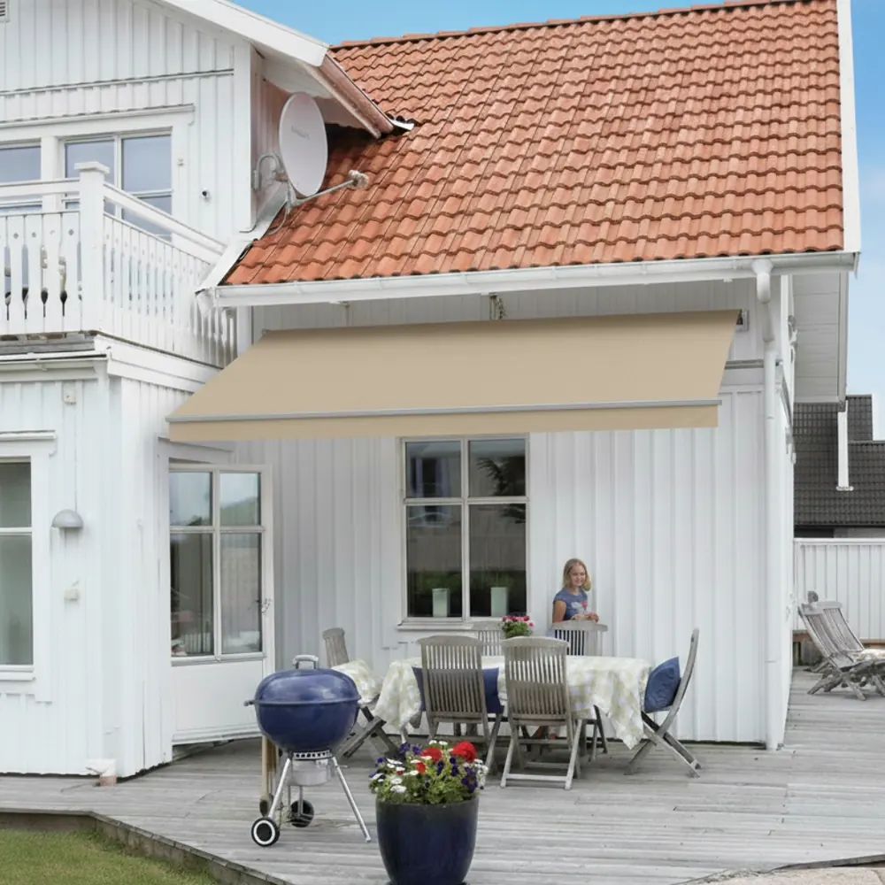 Terrassmarkis i sandfärgad väv monterad över en uteplats på ett vitt hus