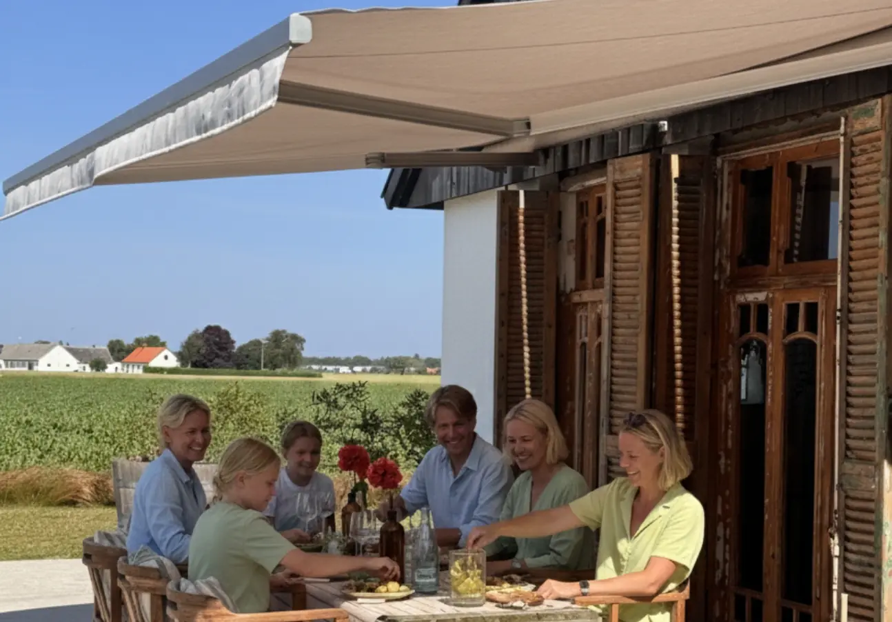 Utfälld terrassmarkis över en uteplats med matbord på en svensk villa